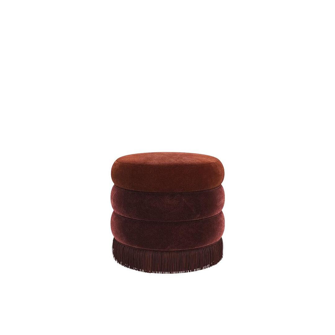 A luxurious Audrey stool by Ottiu in a monochromatic warm palette, featuring three tiers of deep burgundy and rust velvet with matching dark red fringe at the bottom.