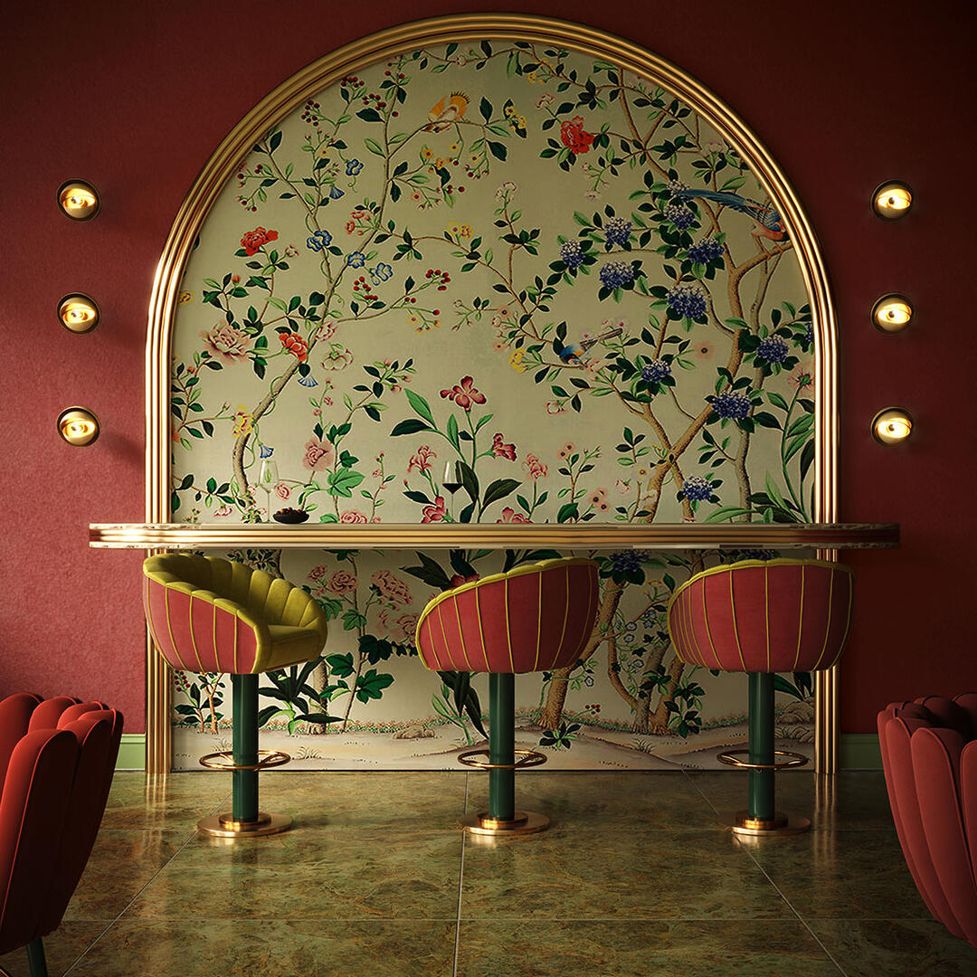 Three Vivien Swivel bar chairs upholstered in red and greenish-yellow fabrics, featuring lacquered green legs and polished brass details. The setting includes a floral wallpaper in an arched wall, two red Angel dining chairs, and six Mandevilla wall lamps.