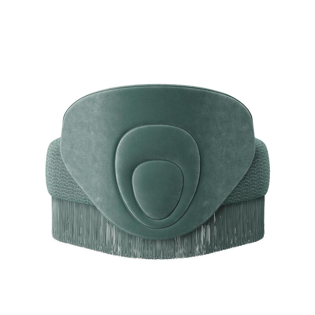 Doris armchair shown from the back. The piece highlights a lavish composition, exquisitely hand-upholstered in sumptuous turquoise velvet fabrics, elegantly draped with cascading fringes that exude grandeur. Upholstered in Dedar fabrics: Ripley and Plushy.