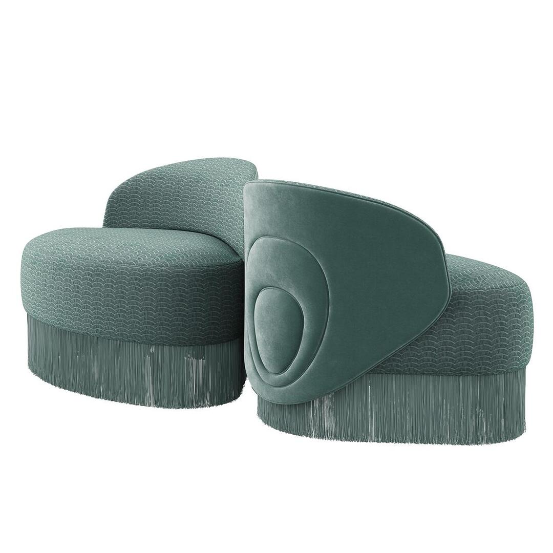 Two Doris armchairs displayed from 45º front and back angles. They reveal a lavish composition, exquisitely hand-upholstered in sumptuous turquoise velvet, adorned with cascading fringes that exude grandeur. Finished in Dedar fabrics: Ripley and Plushy.