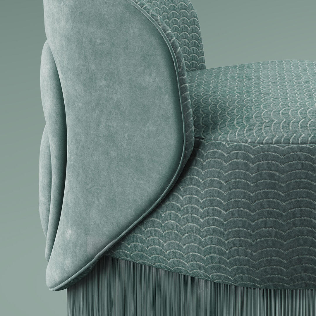 Close-up of the Doris armchair. The design showcases a lavish composition, exquisitely hand-upholstered in sumptuous turquoise velvet and adorned with cascading fringes that exude grandeur. Finished in Dedar fabrics: Ripley and Plushy.