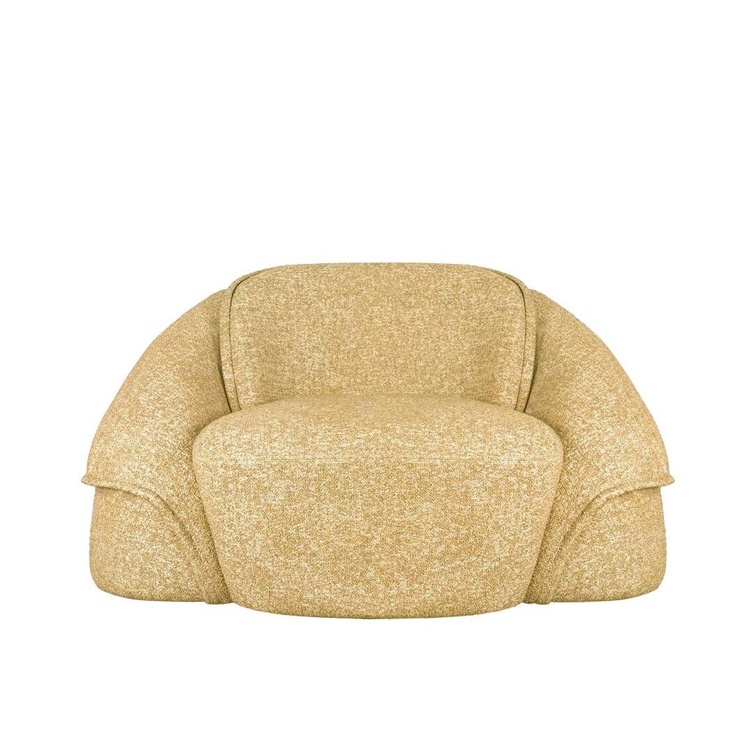 Front view of the Romy armchair in a warm, golden-yellow color variation. The textured fabric highlights the chair’s organic, curved silhouette and the soft, rounded edges of the seat and overlapping backrest panels.
