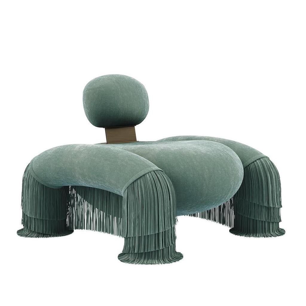 45-degree front view of the Odessa Armchair with backrest pulled-up and fringes, upholstered in Dedar Plushy 147 and Sirgaria Castro Seda 111, paired with aged brass.