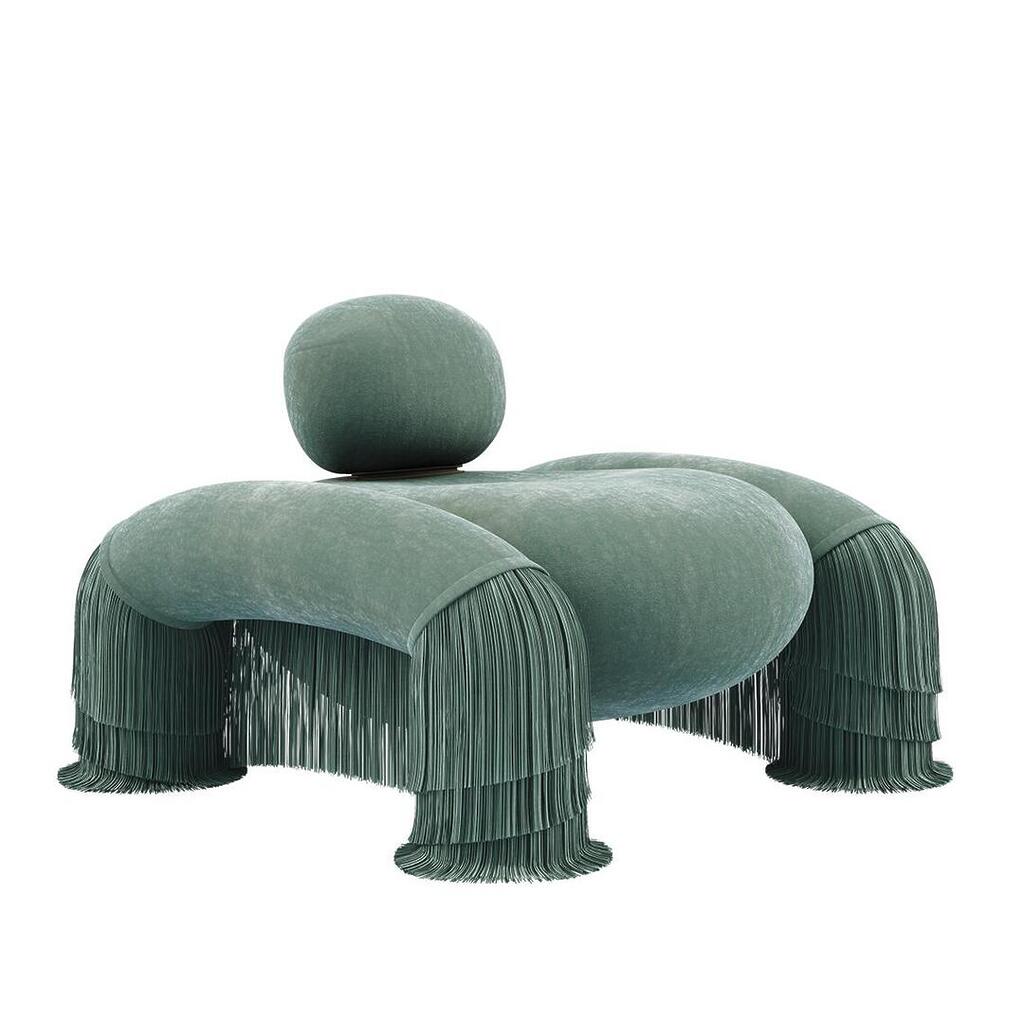 45-degree front view of the Odessa Armchair with backrest down and fringes, upholstered in Dedar Plushy 147 and Sirgaria Castro Seda 111, paired with aged brass.