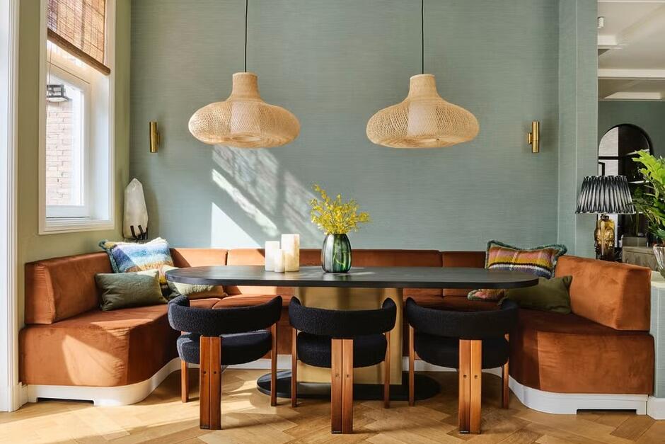 banquette-seating-atelier-nd-amsterdam-home Built-in banquette seating with upholstered cushions along a dining nook, paired with a wooden table and accent pillows, creating a cozy and space-saving dining area.