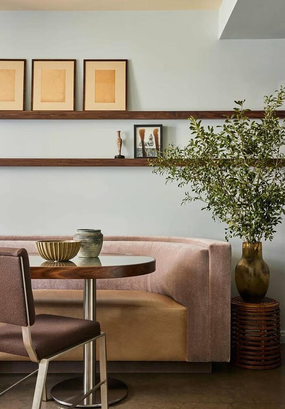 banquette-seating-husband-and-wife Built-in banquette seating with upholstered cushions along a dining nook, paired with a wooden table and accent pillows, creating a cozy and space-saving dining area.