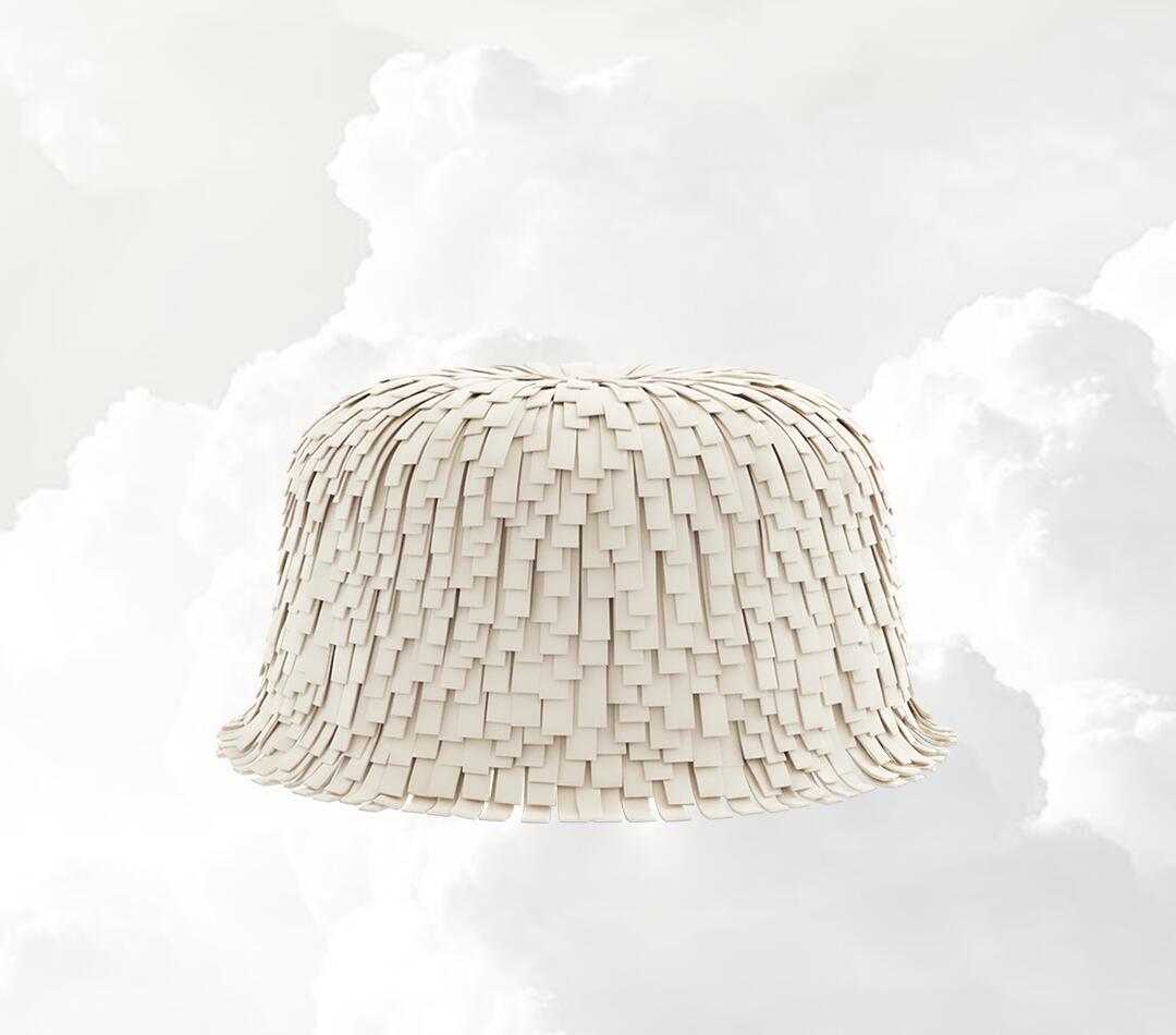 Lyra Ottoman with fringes, upholstered in the new Pantone Color of the Year Cloud Dancer, set against a soft cloud background.