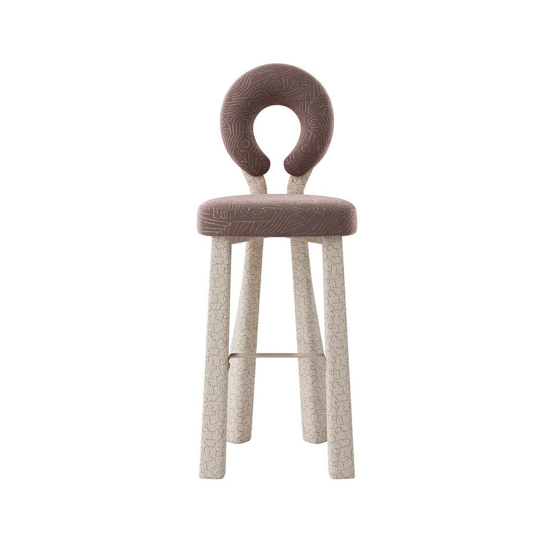 Frontal view of the Mary Bar Chair highlighting its symmetrical, sculptural open-back. The plush seat is covered in a geometric-patterned velvet, supported by sturdy legs upholstered in a contrasting cream bouclé fabric.