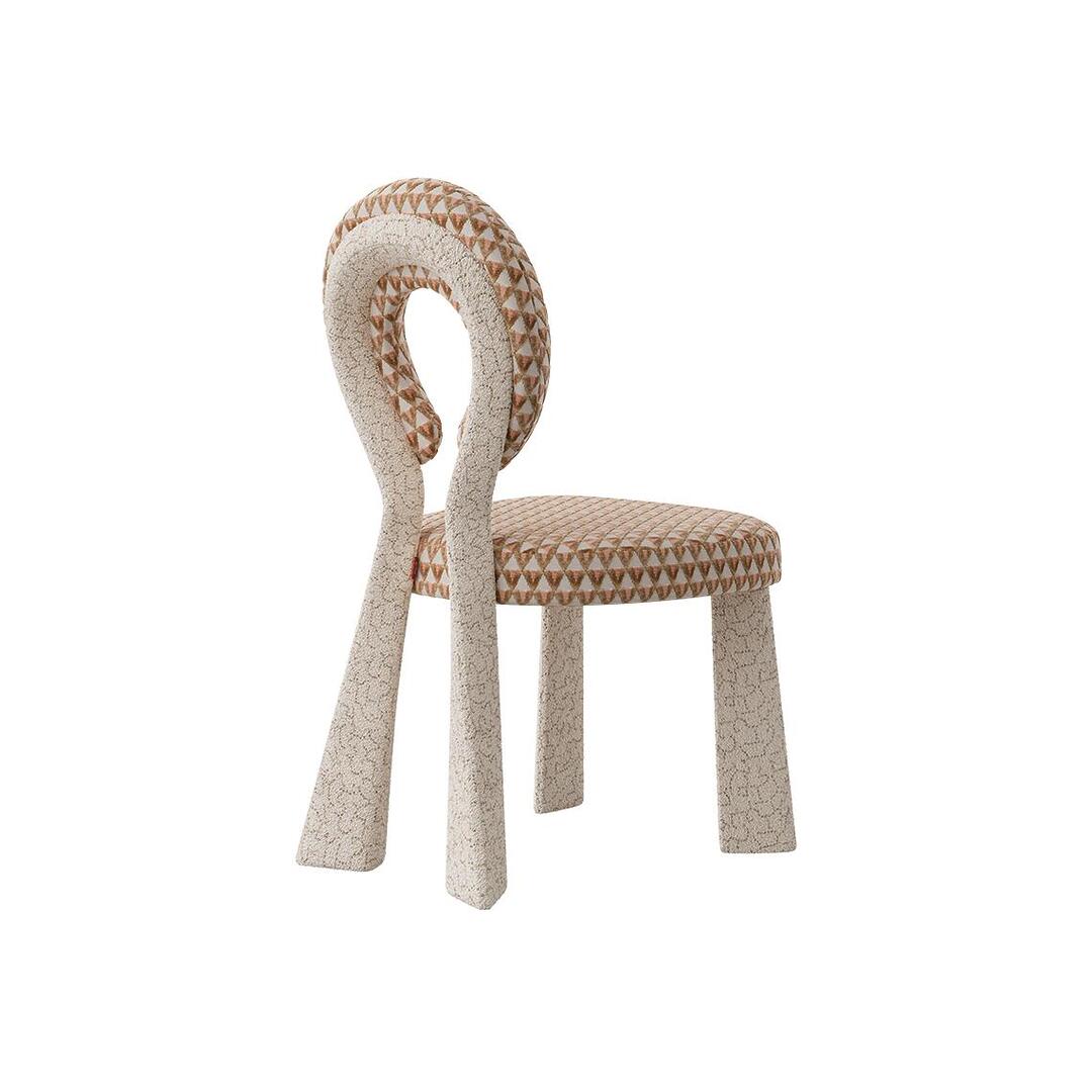 Three-quarter rear view of the Mary Dining Chair featuring a sculptural open-back. The chair is upholstered in a cream bouclé frame paired with a seat and backrest in a sophisticated white and terracotta triangular geometric pattern.
