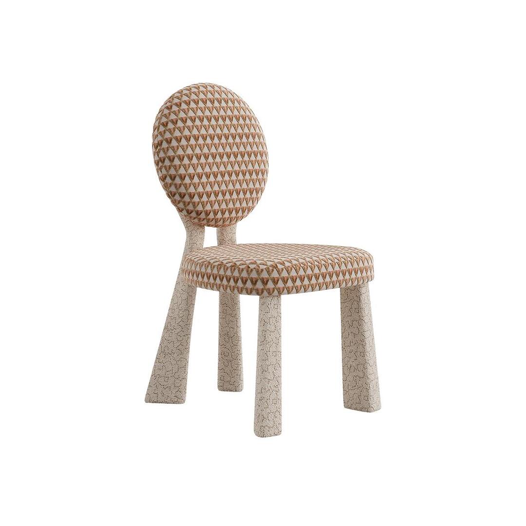 Three-quarter front view of the Mary Dining Chair in the fully upholstered version, where the backrest is a solid circle of patterned geometric fabric.