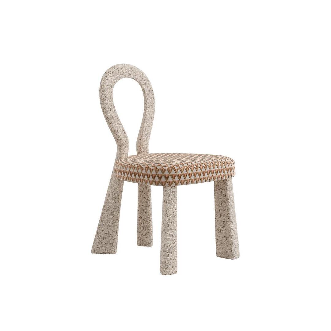 Three-quarter front view of the minimalist Mary Dining Chair, where the entire sculptural open-back frame is upholstered in cream bouclé, leaving only the seat in a patterned fabric.
