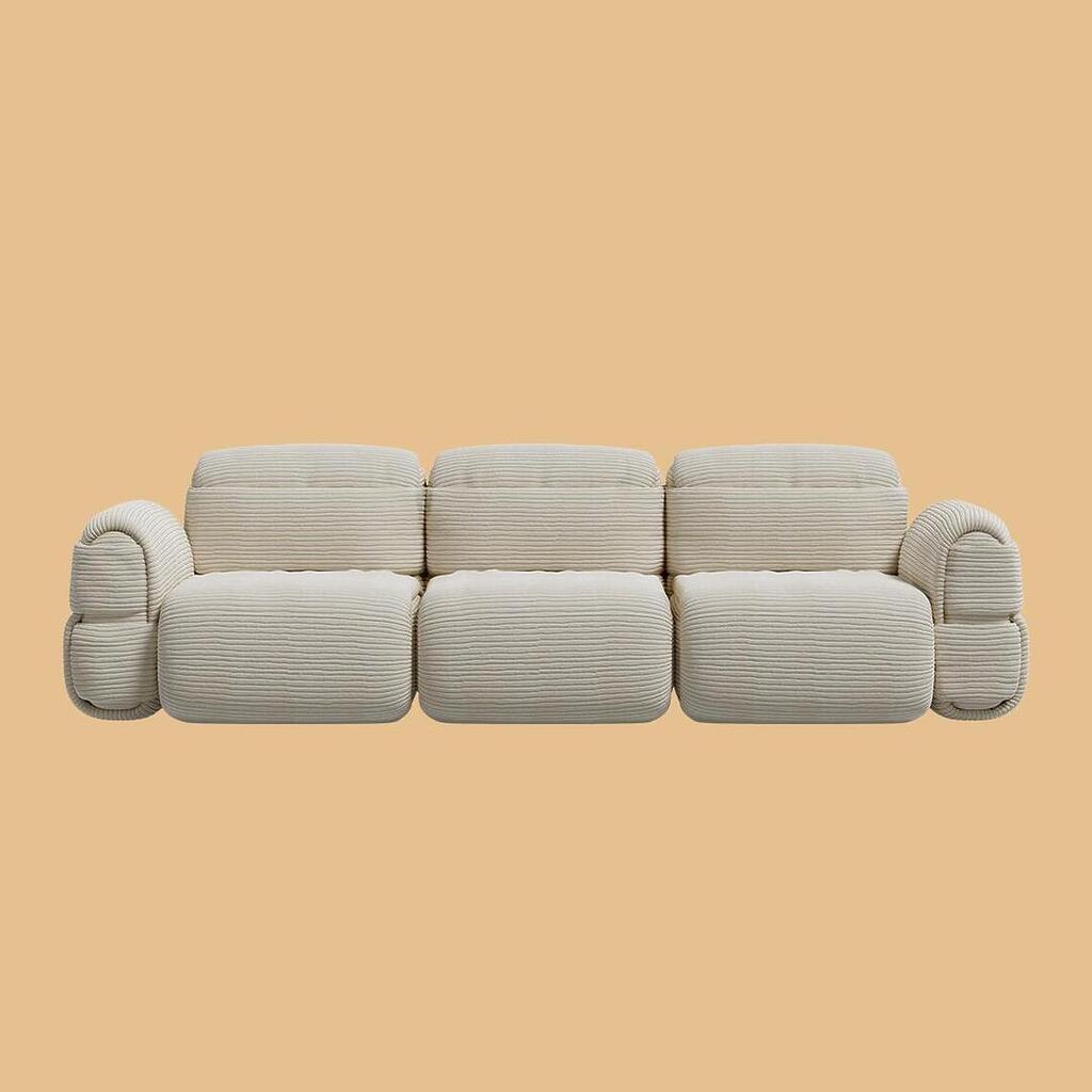 The Elsa Modular Sofa, viewed from the front. A bold, sculptural three-seater sofa with thick armrests and three connected seating modules, uniformly upholstered in an off-white, horizontally ribbed fabric.