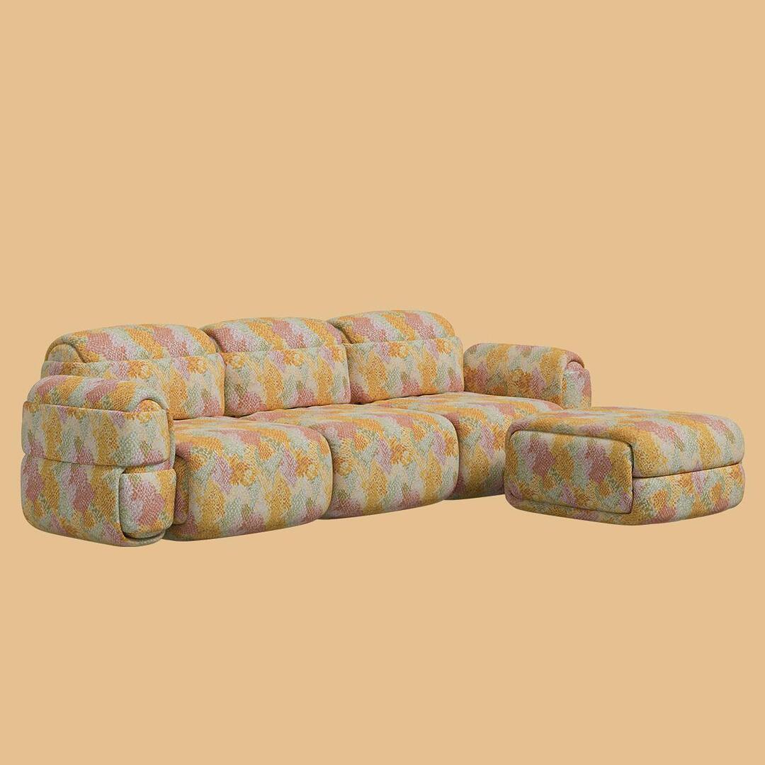 The Elsa Modular Sofa configured in a 3-seater arrangement with a matching ottoman positioned to the right to create an L-shaped chaise section. The entire set is upholstered in a textured fabric with an all-over abstract pattern.