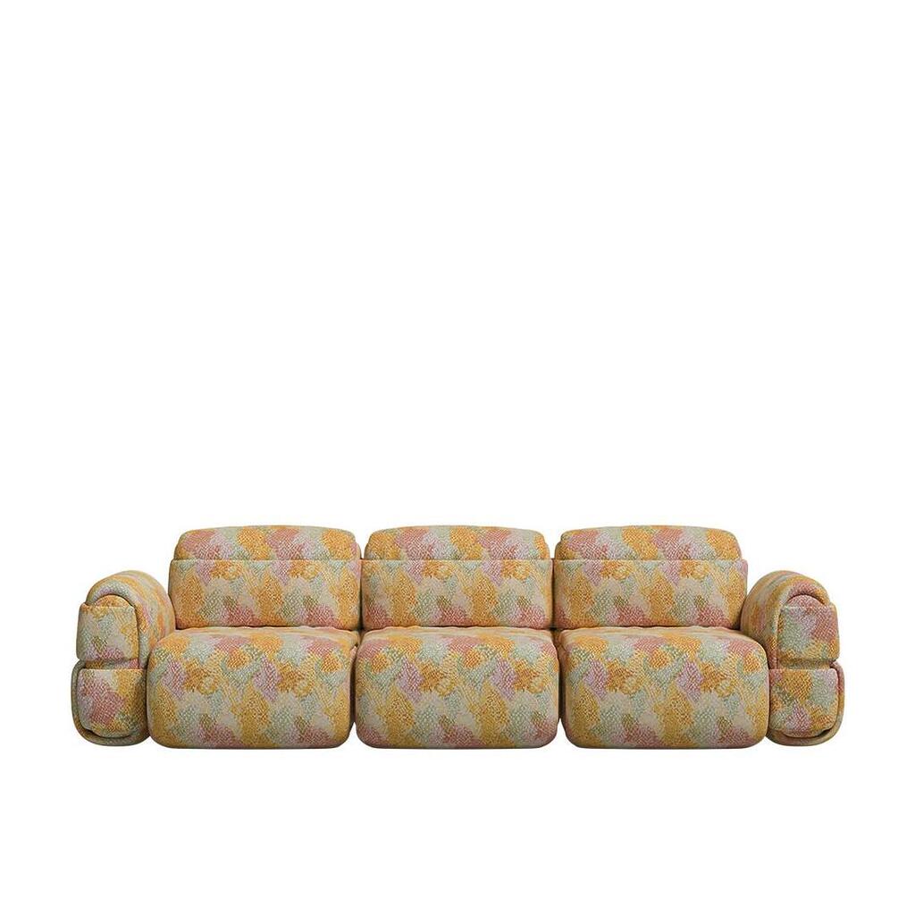 Front-facing view of the Elsa Modular 3-seater sofa, showcasing its voluminous silhouette and soft horizontal padded rolls. The sofa is wrapped in a vibrant abstract patterned fabric.