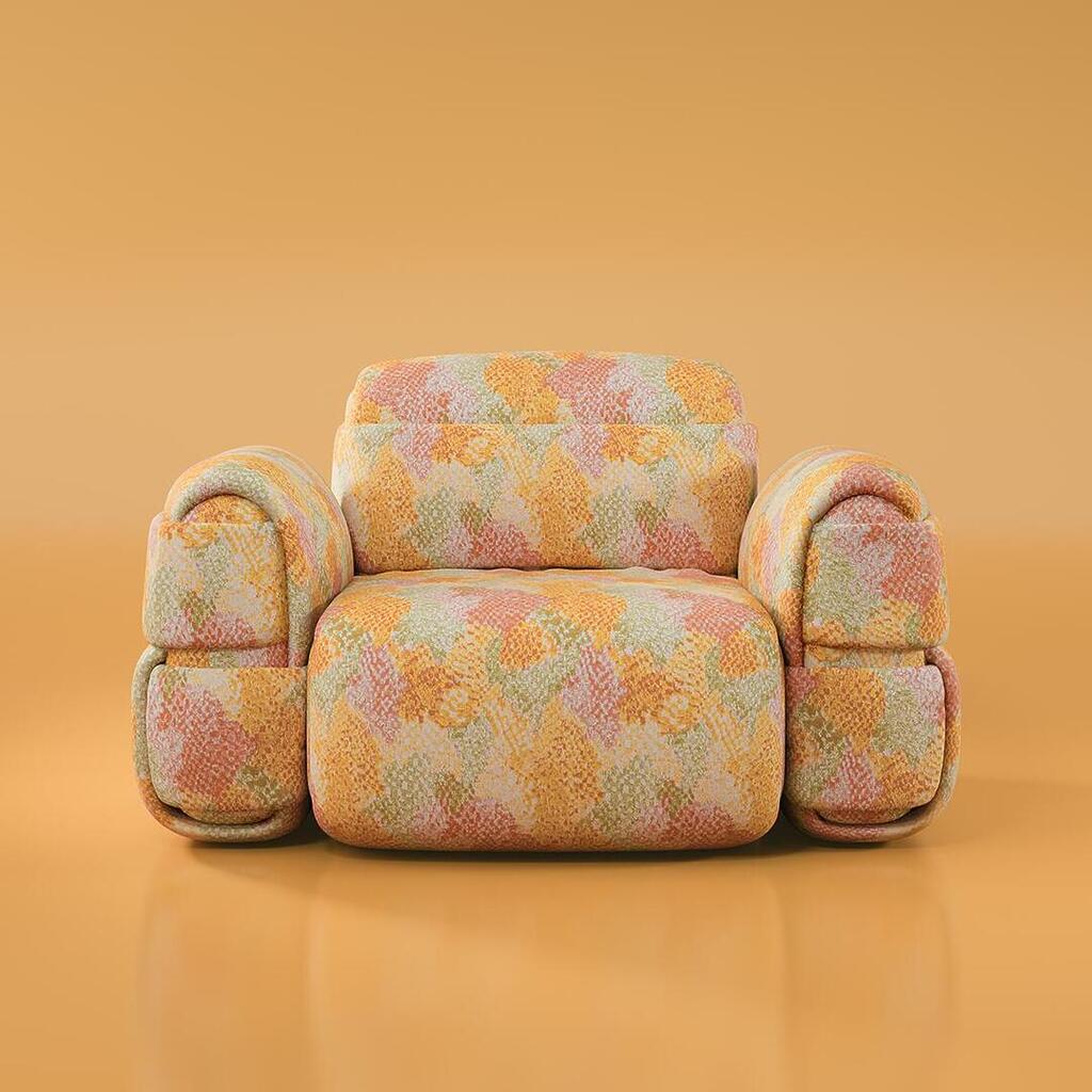 The Elsa Armchair, shown in its front-facing configuration, is a bold statement piece with a unique, bulbous design. Fully upholstered in a textured, geometric patterned fabric featuring colors of sunny yellow, soft coral, peach, and muted green, the chair has a distinctly 1970s feel. It is composed of a massive, rounded central seat and back module, flanked by two extremely oversized, segmented block armrests, creating a sense of a cozy, enclosed pod. The chair sits low to the ground against a smooth, reflective orange studio background.