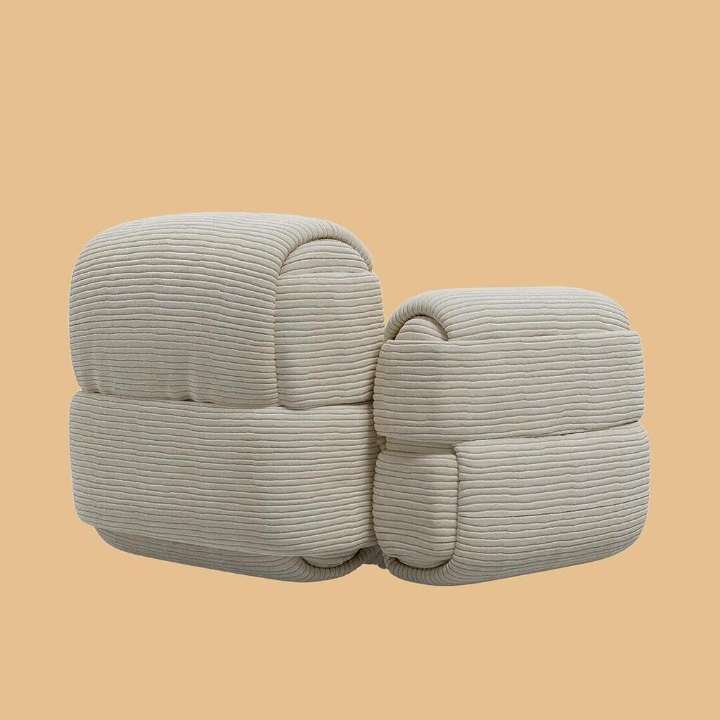 The Elsa Modular Armless Chair, shown from a rear-angled perspective. This modular seating piece features a thick, rounded base and a matching curved backrest, upholstered entirely in an off-white, horizontally ribbed fabric.