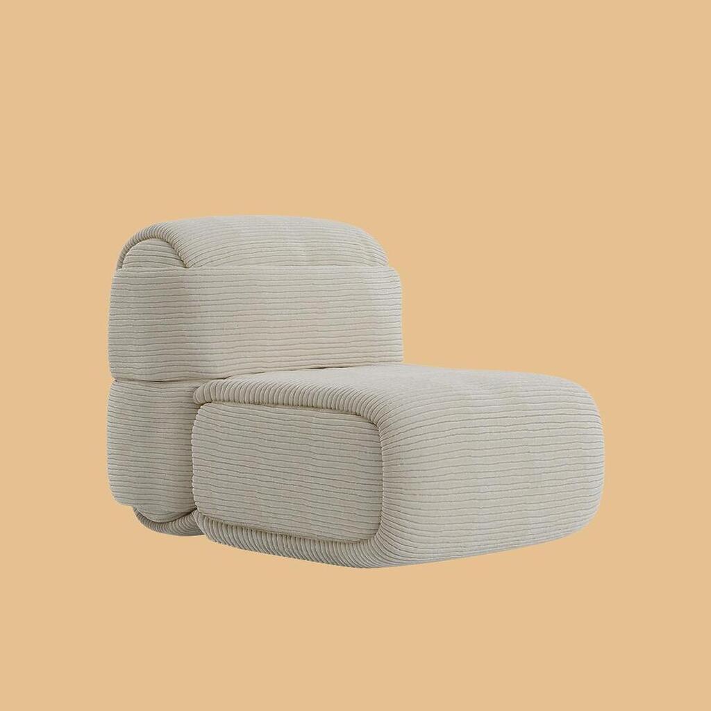 The Elsa Modular Armless Chair, viewed from a front angle. The design highlights a plush, voluminous seat cushion and a curved backrest, offering a clean, streamlined silhouette without armrests. The piece is covered in an off-white, horizontally ribbed fabric.