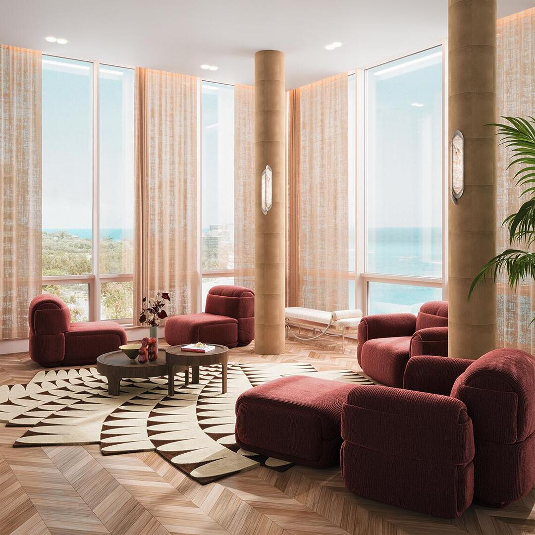 O Gemini disse An elegant modern lounge featuring the Elsa modular armchair collection by Ottiu, showcasing a sense of sculptural comfort in deep burgundy textured upholstery. The space is anchored by a Churchill center table by Wood Tailors Club and illuminated by Glacier wall lamps by Porus Studio mounted on suede-wrapped columns, all set against a backdrop of floor-to-ceiling windows with a serene ocean view.