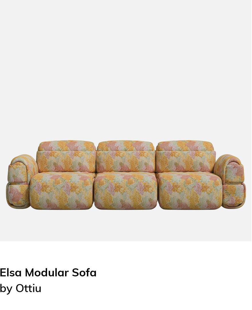 Front-facing view of the Elsa Modular 3-seater sofa, showcasing its voluminous silhouette and soft horizontal padded rolls. The sofa is wrapped in a vibrant abstract patterned fabric.