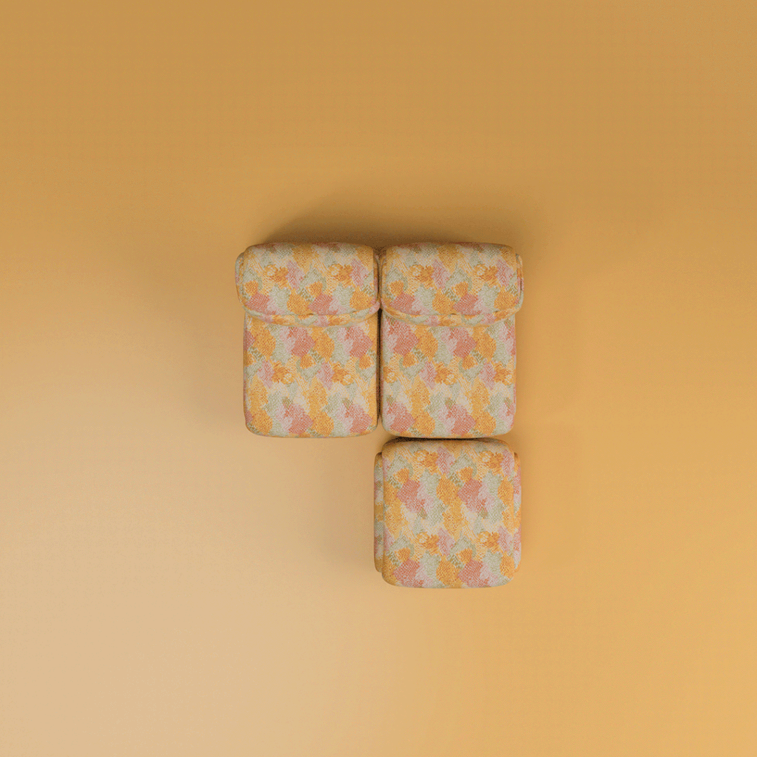 An animated GIF showcasing a top-down view of the Elsa Modular Sofa. The animation demonstrates various seating components—including armless modules, end pieces with thick armrests, and an ottoman—sliding together to form different seating configurations. All pieces share a voluminous, pillowy design and are upholstered in a textured fabric featuring a colorful geometric mosaic pattern in warm shades of yellow, coral, peach, and sage green.