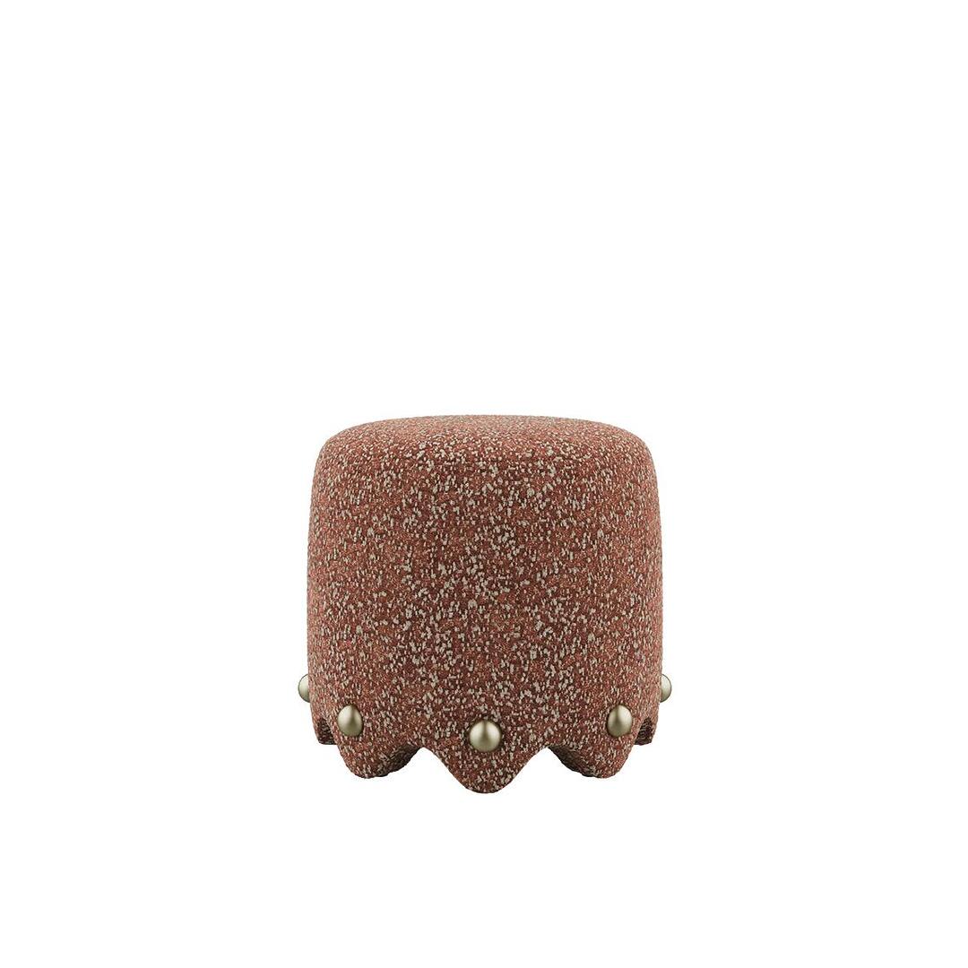A front-view studio shot of the Bette Stool by Ottiu, featuring a robust, cylindrical silhouette upholstered in high-tactile Élitis Mochi fabric in a rich rust tone. The base is defined by a sculptural, scalloped hemline punctuated with spherical polished brass studs.