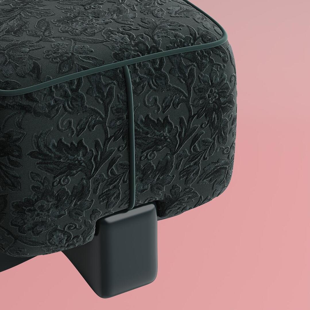 A macro detail shot of the Pola Stool in forest green velvet, highlighting the intricate raised floral embroidery, fine piping, and the seamless integration with the dark lacquered base against a soft pink background.