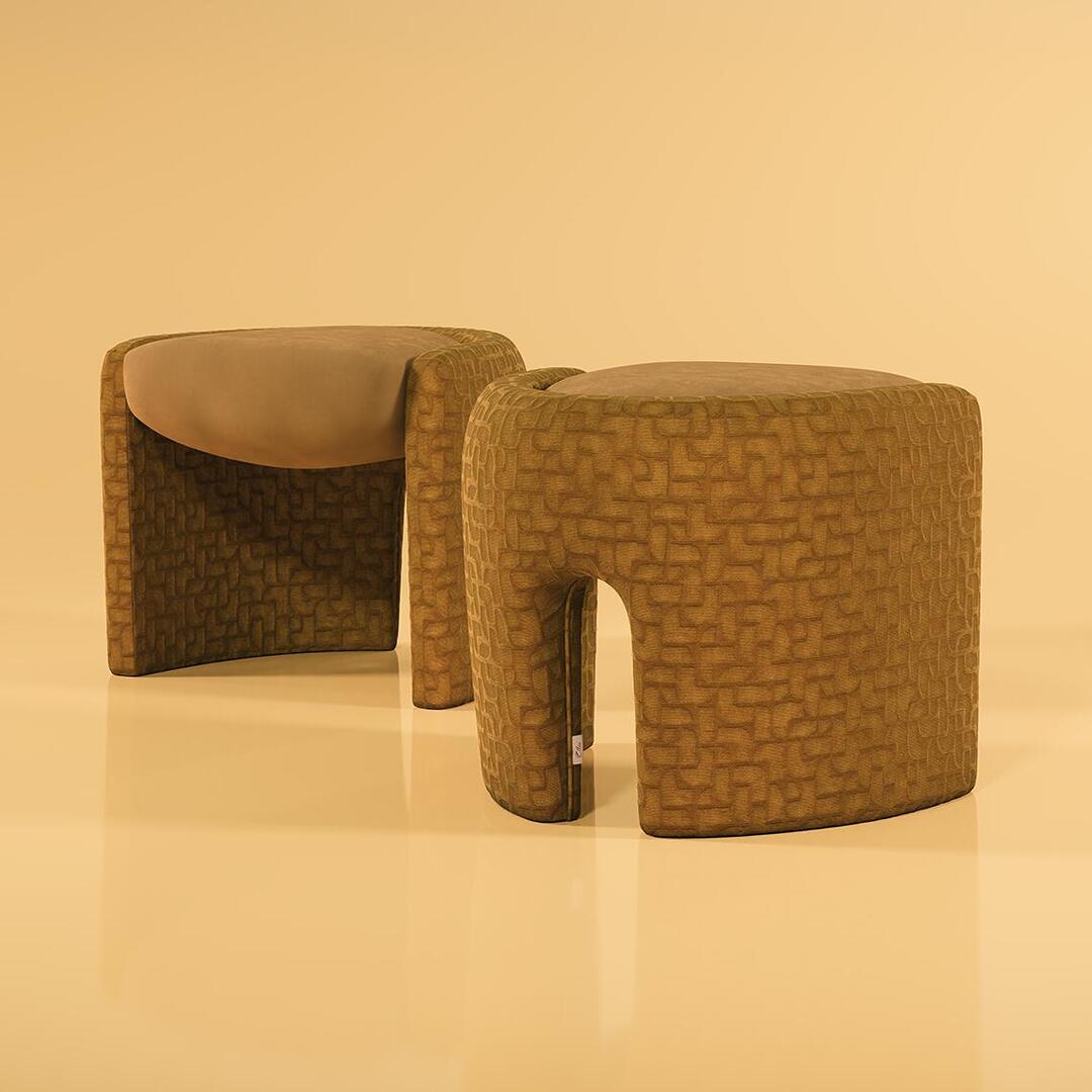 Two Grace Stools by Ottiu are displayed against a smooth, solid light-ochre background. The stool in the foreground highlights its curved, sculpted back upholstered in a golden-brown textured velvet with an intricate geometric pattern, featuring a distinctive arch-like cutout base. The second stool in the background faces slightly away, showcasing the smooth, matching beige suede seat cushion cradled within the rounded frame. Their glossy reflections are visible on the polished floor.