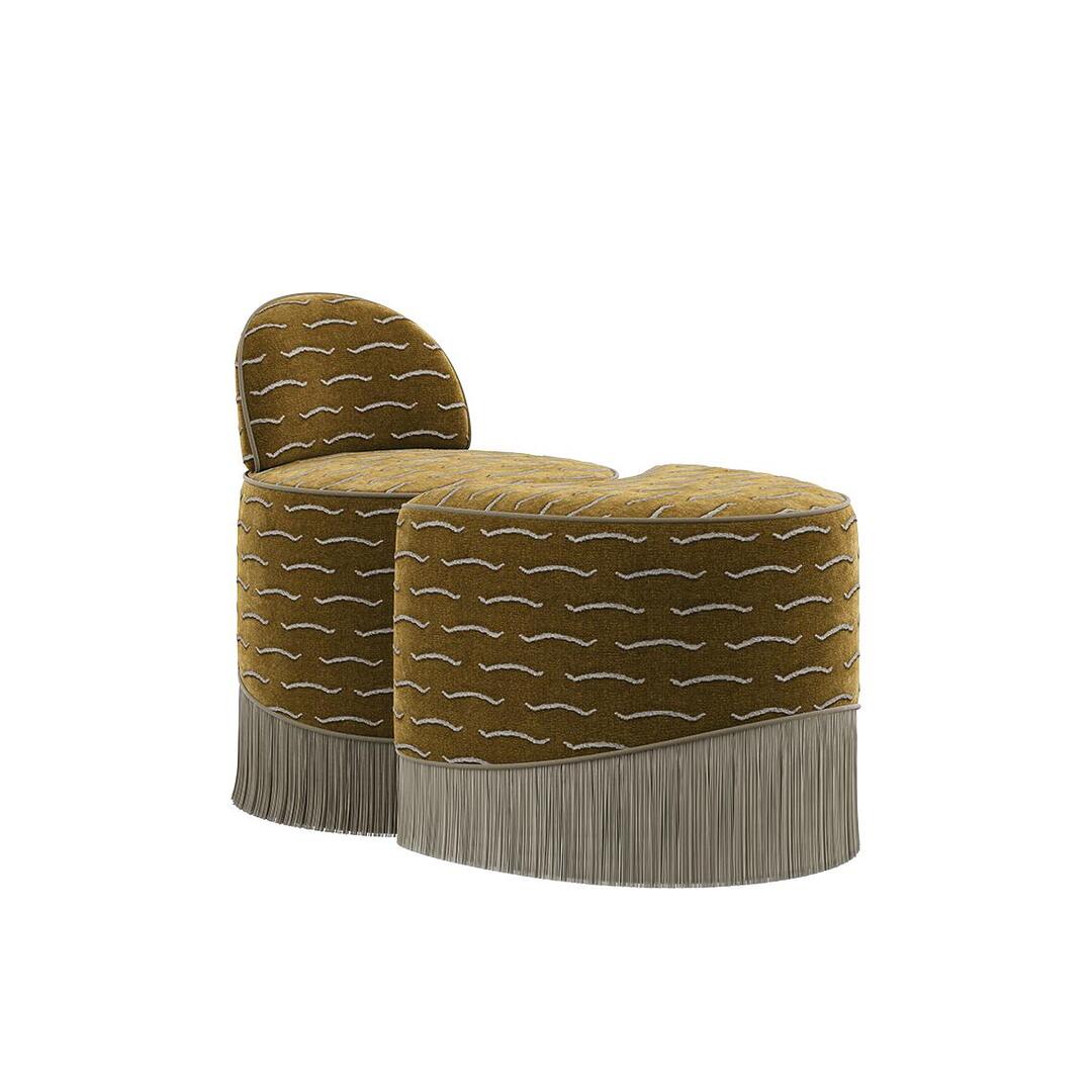 A front-facing three-quarter view of the Lila Stool by Ottiu. The piece consists of two nested, modular sections upholstered in a rich ochre-gold jacquard velvet with a wavy white pattern. The rear section includes a curved, low backrest, while the front section is a crescent-shaped ottoman. Both pieces are finished with a long, dense fringe skirt in a neutral cream tone along the bottom edge.
