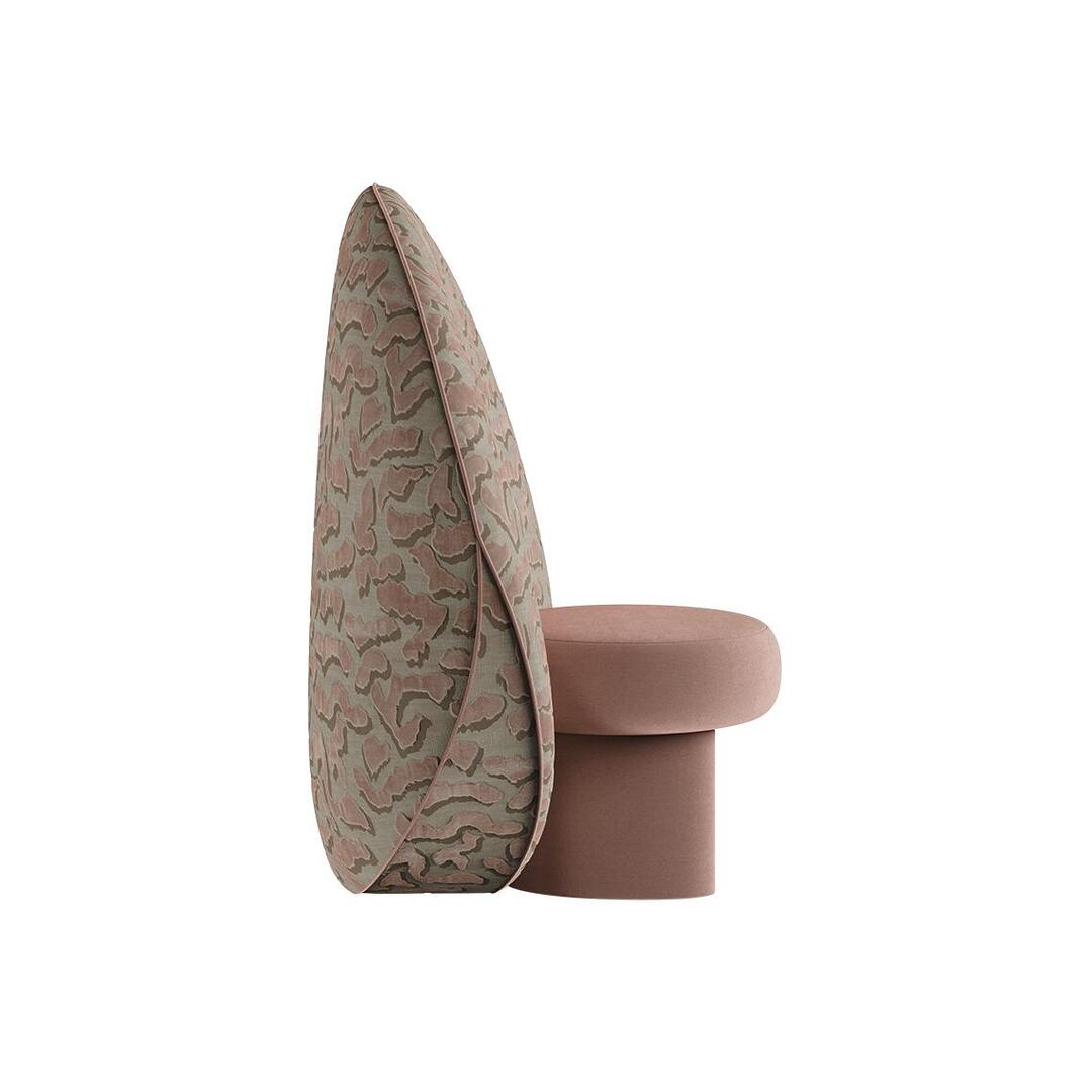 Side profile view of the Solène Armchair by Ottiu, showcasing its unique geometry. The low pink velvet stool section seamlessly nests against a massive, tapered circular backrest that features a thick, teardrop silhouette when viewed from the side, detailed with elegant fabric piping along the edge.