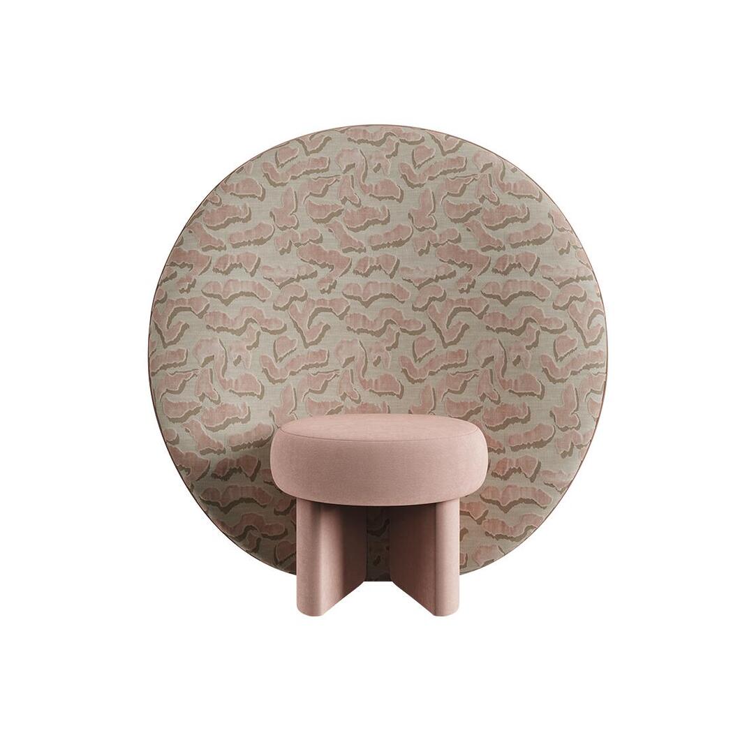 Front view of the Solène Armchair by Ottiu, featuring a round, low-set cushion seat and architectural cross-base upholstered in soft pink cotton velvet. Rising behind the seat is a massive circular back panel upholstered in a textured , organic pattern in shades of rose pink and muted beige.