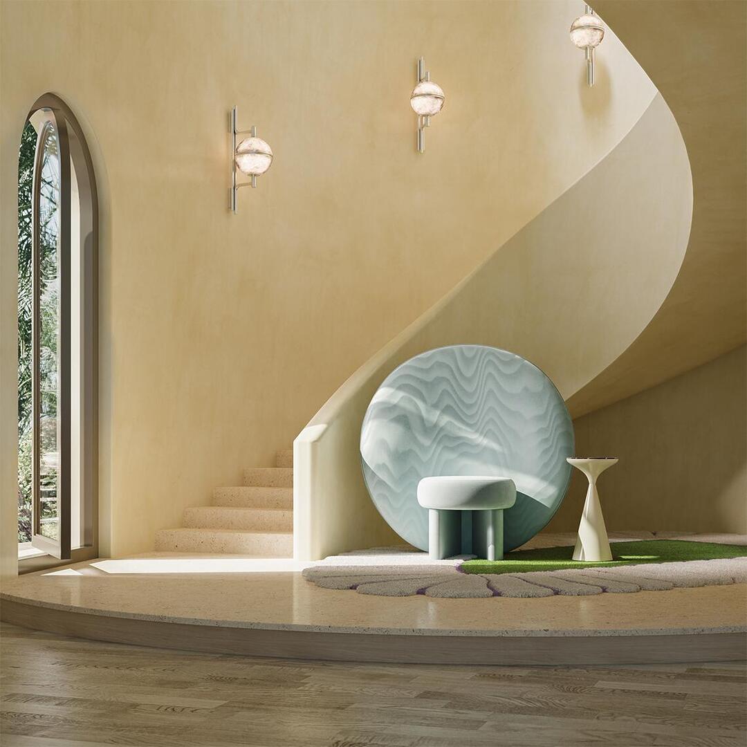 The ice-blue Solène Armchair placed on a textured, leaf-shaped rug next to a sweeping concrete spiral staircase in a minimalist, sun-drenched Mediterranean interior with warm plaster walls. Next to the armchair is the Lignum side table and Androw wall lamps.