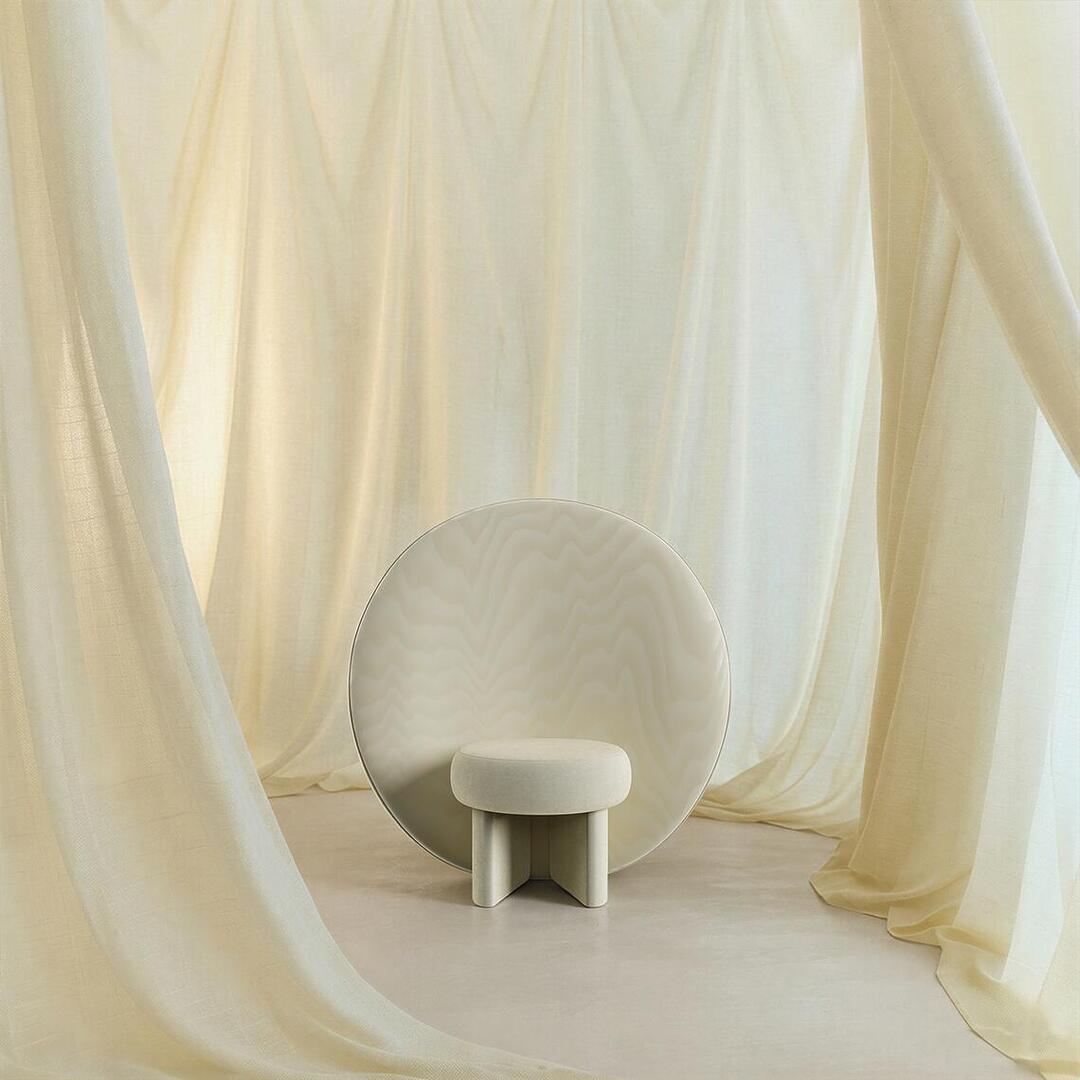 The cream-colored Solène Armchair positioned at the center of an elegant, ethereal room filled with layers of softly draped, matching ivory linens creating a cozy, monochromatic sanctuary.