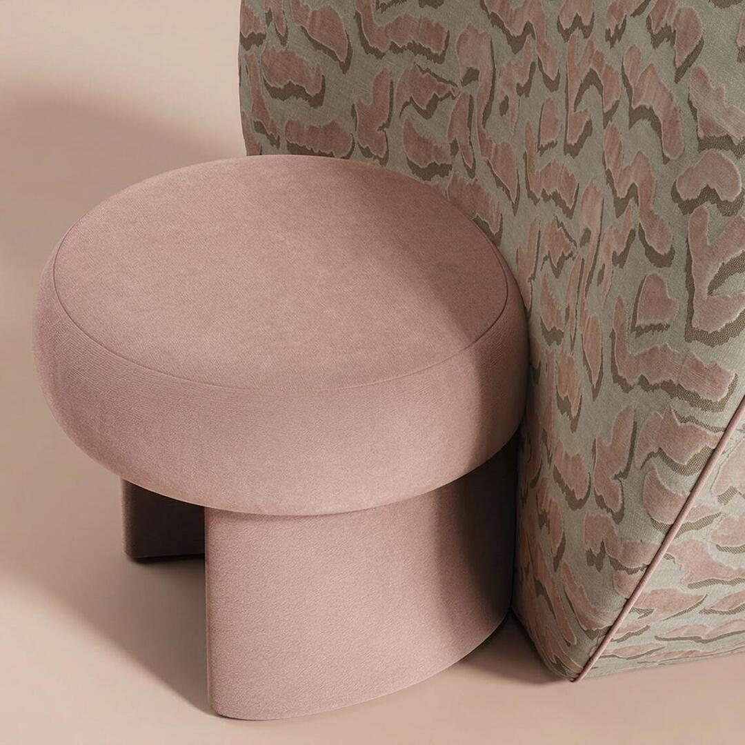 A detailed close-up, high-angle shot of the Solène Armchair by Ottiu. The image highlights the smooth texture of the round pink velvet seat cushion and its curved base, juxtaposed against the intricate, wavy pattern of the pink and sage green velvet jacquard on the large back panel, resting on a matching soft pink surface.
