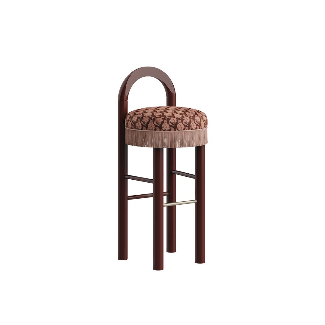 Three-quarter view of the Ann Bar Chair with rich dark lacquered wood legs, a floral patterned upholstery seat, matching fringe trim along the base, and a stainless steel footrest.