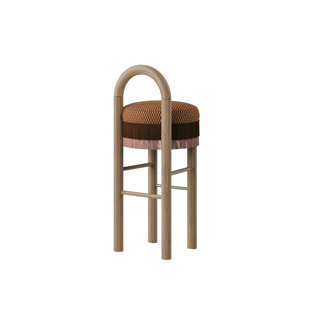 Side angle view of the Ann Bar Chair showcasing the natural wood frame structure, round upholstered seat with dual-layer fringe details, and stainless steel footrests.