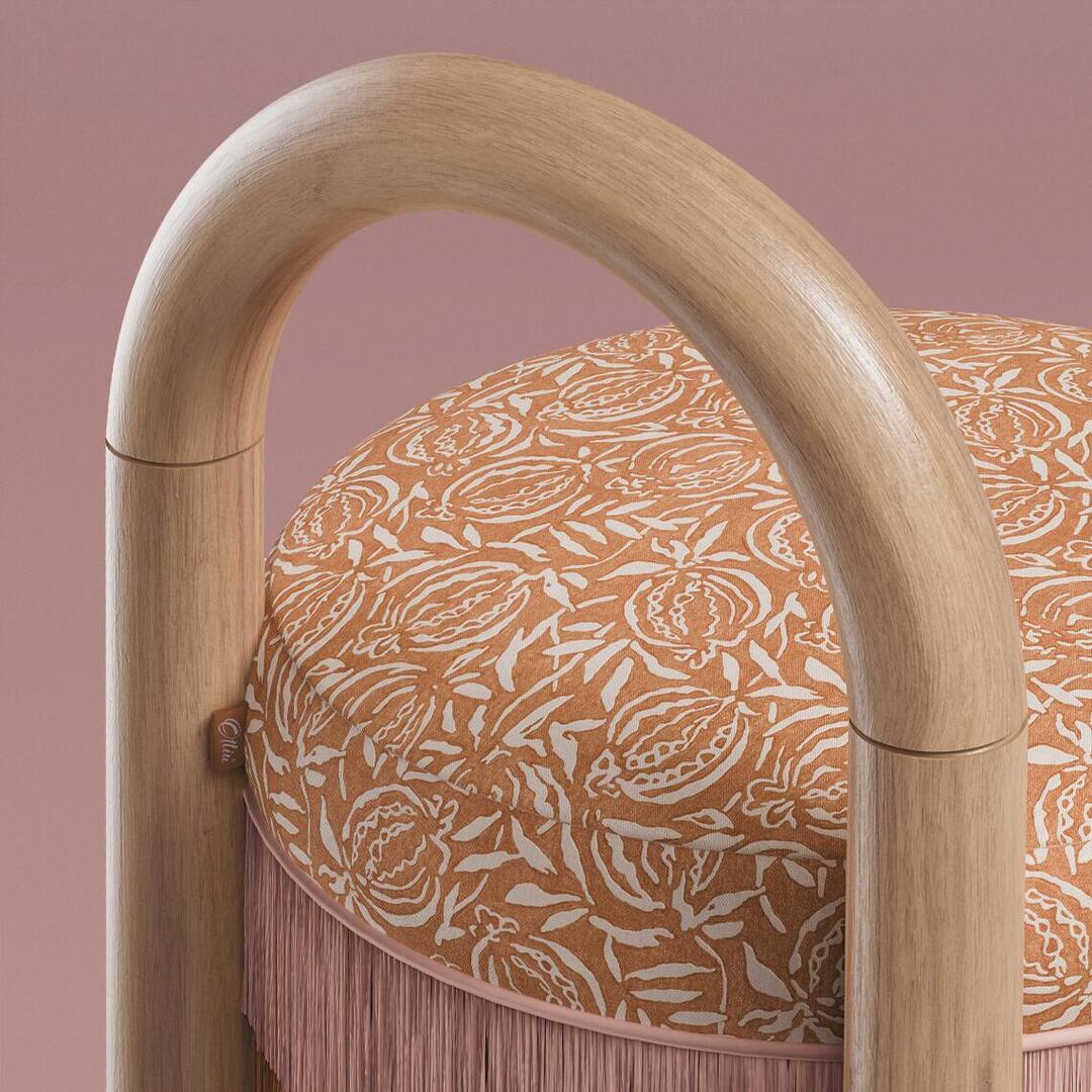 Macro close-up shot of the Ann Bar Chair highlighting the natural wood arched frame, orange floral patterned upholstered seat, and fine pink fringe trim.