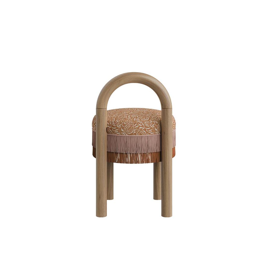 Back view of the Ann dining chair highlighting the continuous arched natural wood backrest frame and layered fringe trim beneath the seat.